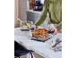 Person holding a dish of roasted chicken and vegetables, with a gratin dish nearby.