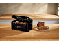 Loaf and bread rolls in a black bread bin with '1973' inscription on a wooden counter.
