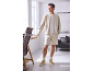 Man in a beige bomber jacket, shorts, and sneakers, posing in a bright office.