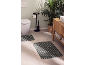 Bathroom with two striped bath mats, toilet, plant, and wooden vanity.