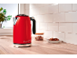 Red electric kettle with '1973' text on a wooden countertop with cookies and a jar.