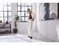 Woman in white short jacket, white wide-leg trousers, and burgundy loafers in a bright interior.