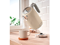 Cream retro kettle pouring hot water into a mug on a wooden kitchen counter.