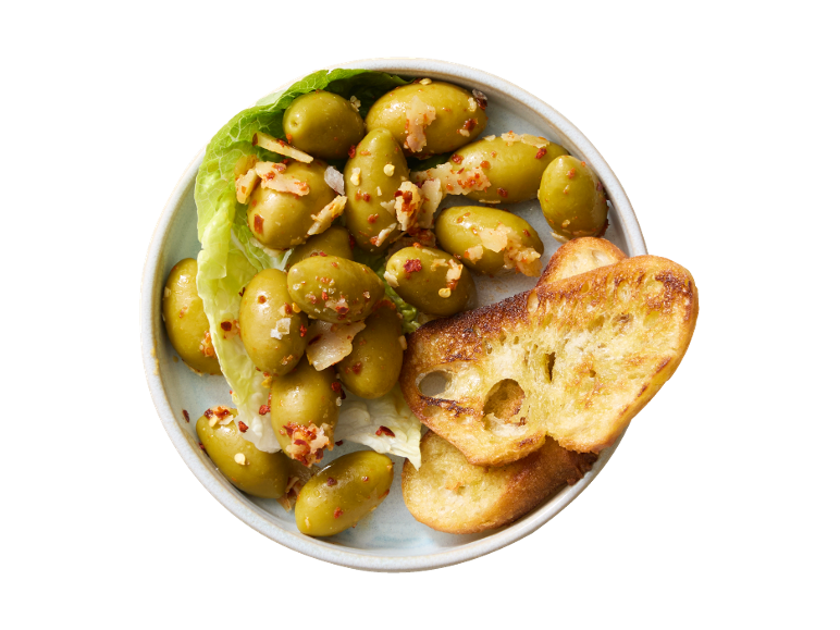 Marinated green olives with chili and garlic, served with toasted bread slices.