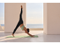 Woman in a sports top and leggings doing yoga on a terrace with a sea view.