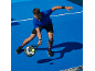 Man in sportswear playing padel on a blue court.