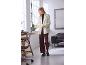 Woman in white blazer and burgundy trousers, holding a tablet in a modern office.