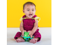 Happy baby in a magenta overall holding a green frog toy.