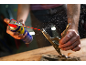Man spraying lubricant on a metal object held by locking pliers.