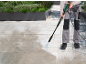 Person cleaning patio with a pressure washer, showing before and after results.