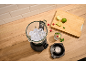 Blender with ice, fruits, and a refreshing drink on a wooden table.