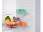 Open refrigerator with a water bottle, mango, oranges, currants, eggplants, and peppers in clear containers.