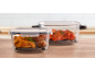 Two glass food containers, one with potato wedges and chicken, the other with chicken wings.