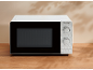 White microwave with a two-dial control panel on a wooden table.