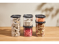 Clear food containers with cereals, legumes, nuts, and dried fruit.
