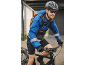 Man on a bike wearing a blue jacket, helmet, sunglasses, and a backpack.