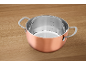 Copper-colored pot with stainless steel interior and measurement markings on a wooden table.
