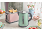 Pink toaster and mint green kettle on a kitchen counter with breakfast items.