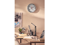 Office desk with a clock, desk lamp, plant, and notice board.