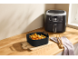 Hot air fryer with a silicone basket full of french fries and onion rings.