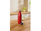 Red insulated bottle with its cap next to a glass of water with lime on a wooden counter.