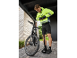 Man in cycling jacket and shorts inflates bike tire with a floor pump.