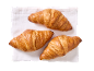 Three golden croissants on a white linen napkin.
