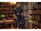 Man in black puffer jacket and jeans, with backpack and books, in an antique library.