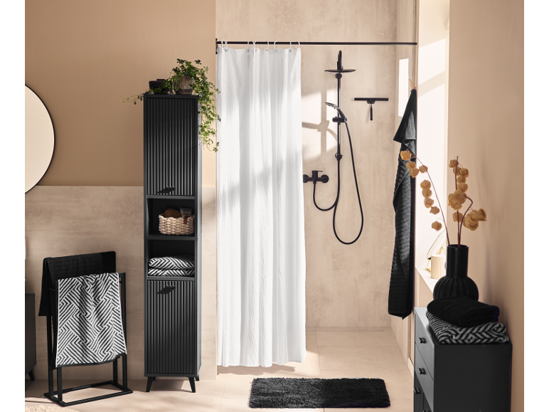 Modern black bathroom furniture set with shower, towels, and decorative elements.