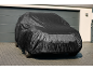 Black car cover covering a car in front of a garage