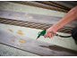 Hand using an air blow gun to clear sawdust from laminate flooring planks.