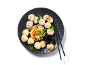Steamed dumplings and bao buns with a side salad and soy sauce on a black plate.