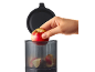 Hand placing a red apple into a transparent chopper with a black lid.