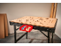 A workbench with a perforated wooden top, holding two red bins with screws and wooden dowels.
