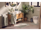 Modern bathroom with green towels, wooden cabinet, sink, and toilet, decorated with plants.