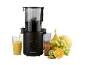 Black juicer with orange juice and assorted fresh fruit on a black background.