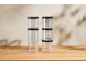 Two stacks of clear food containers with black lids on a wooden table.