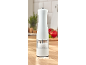 White electric salt mill on a wooden countertop with tomatoes in the background.