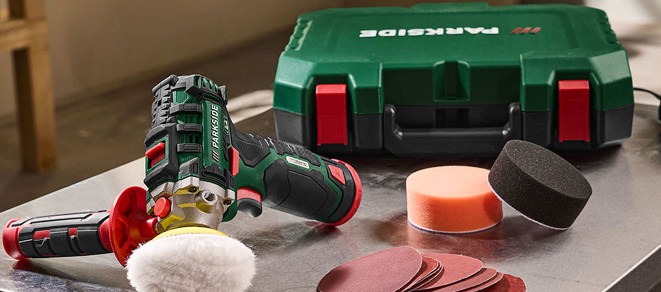 Polisher with accessories and a green tool case on a metallic surface.