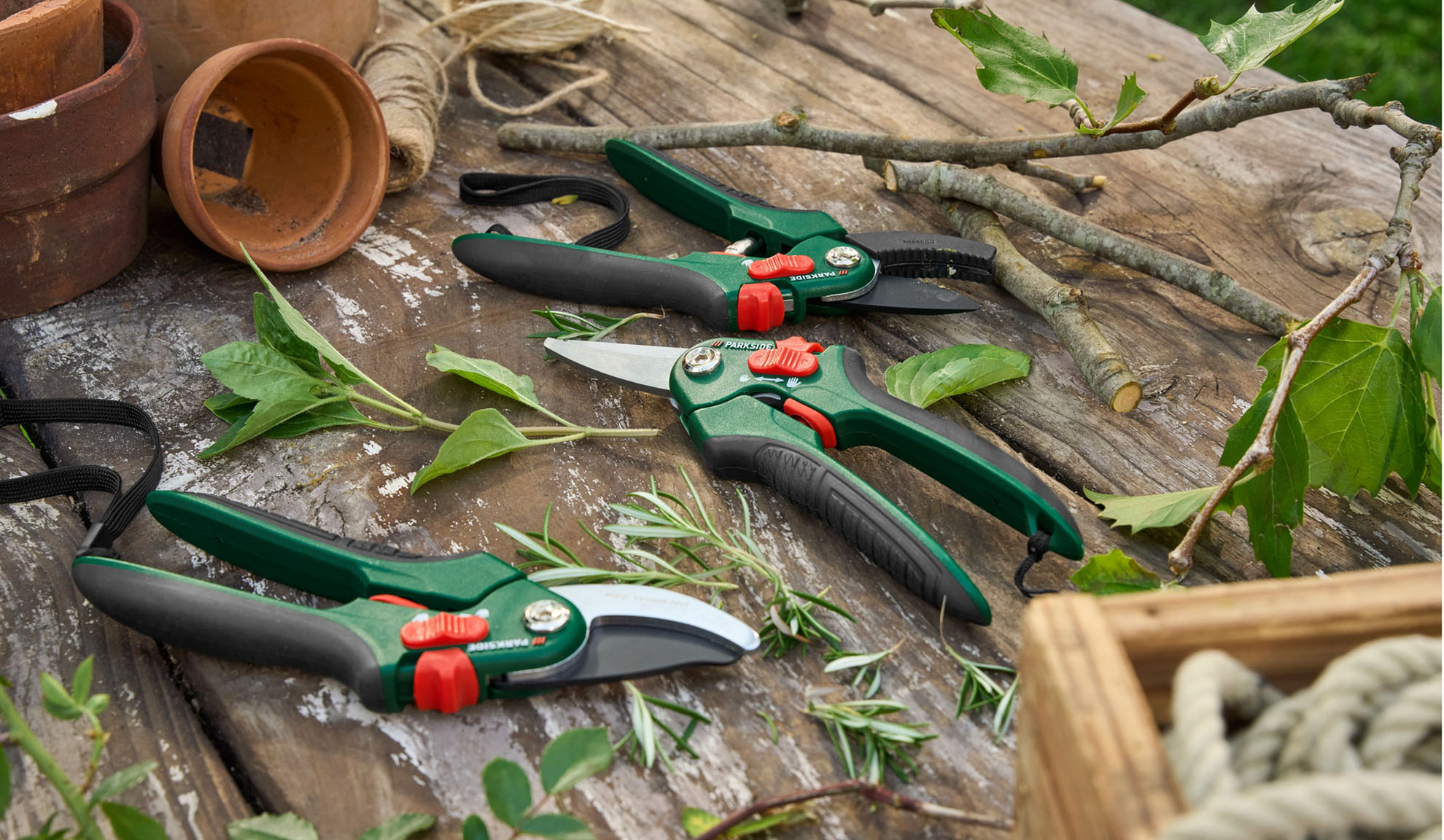 Parkside gardening shears and secateurs lie on a rustic wooden surface with plants and gardening supplies.