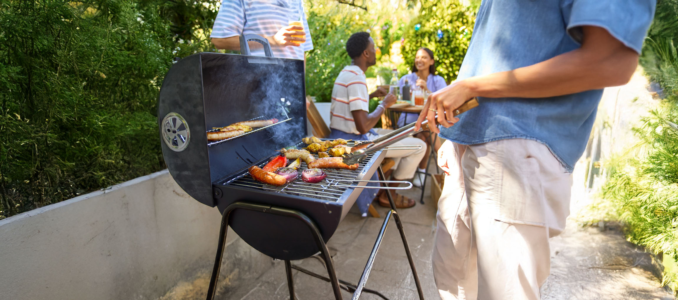 A charcoal grill with sausages and vegetables grilling.