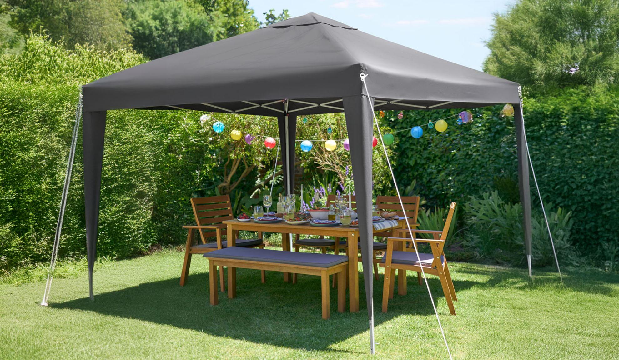 Dark gray garden gazebo with wooden table and chairs.