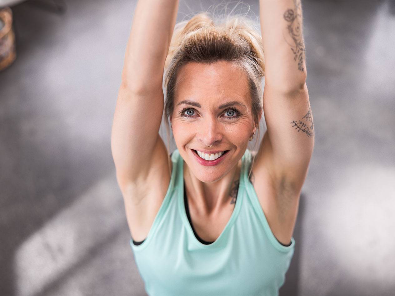 Blonde woman in a light blue tank top smiling at the camera.