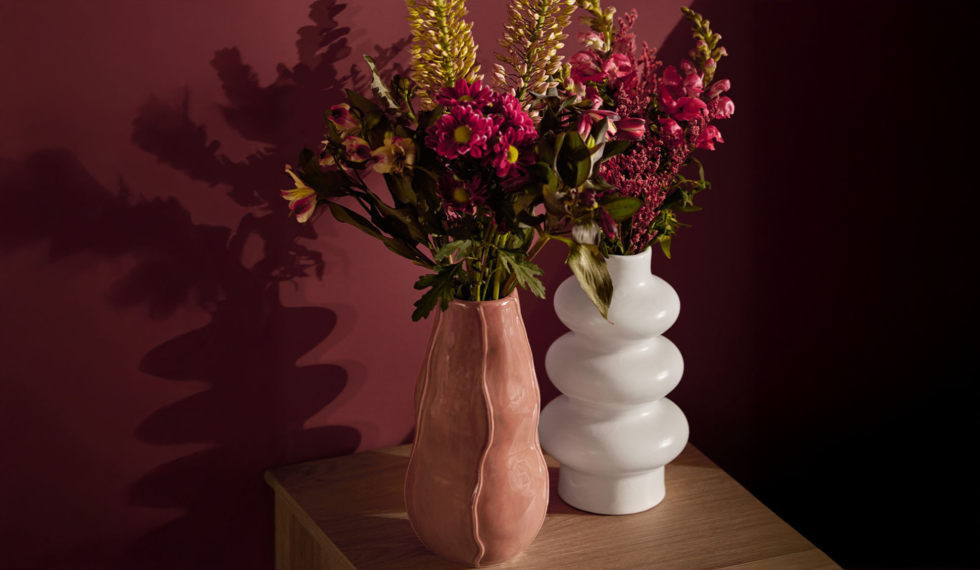 Two vases with colorful flowers on a wooden table.