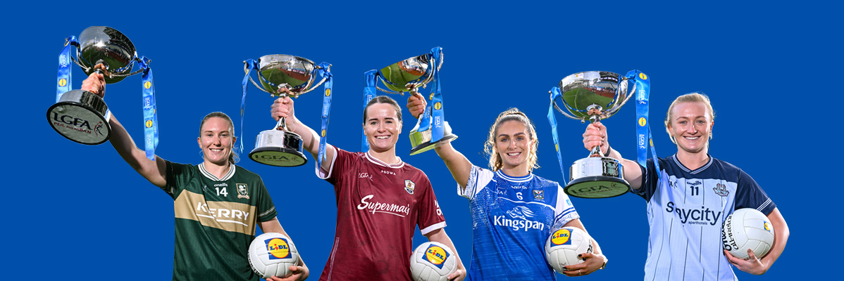 Four female athletes in jerseys holding up trophies and footballs.