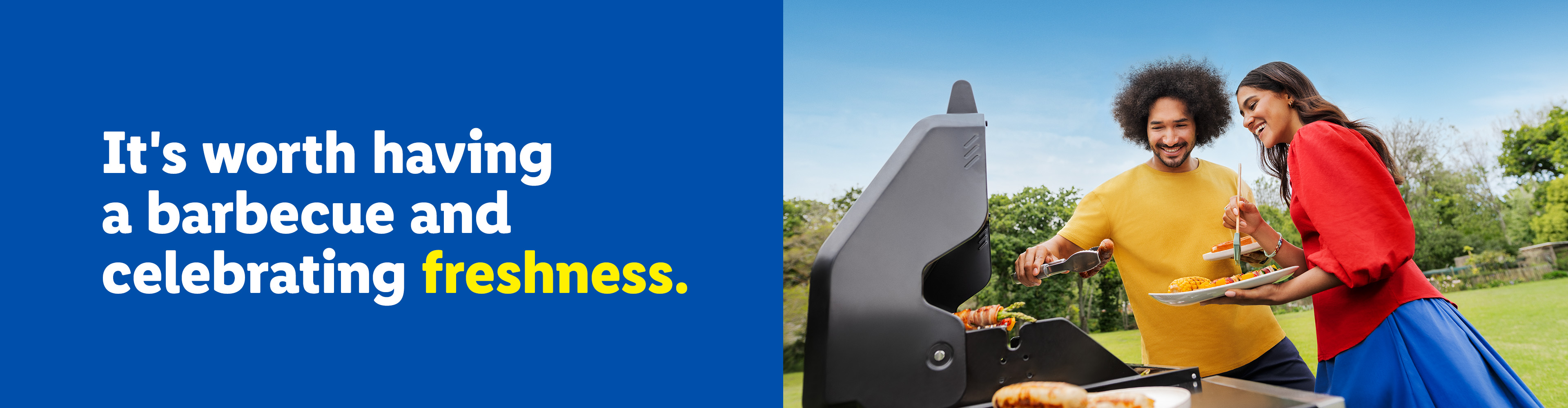 A couple grilling food outdoors, with a man using tongs and a woman holding a plate.