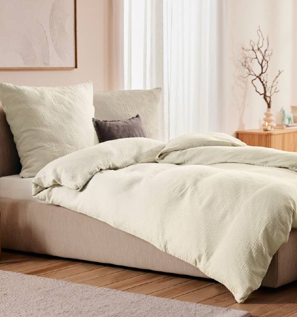 Bedroom with a bed featuring light-colored, textured bedding and pillows.