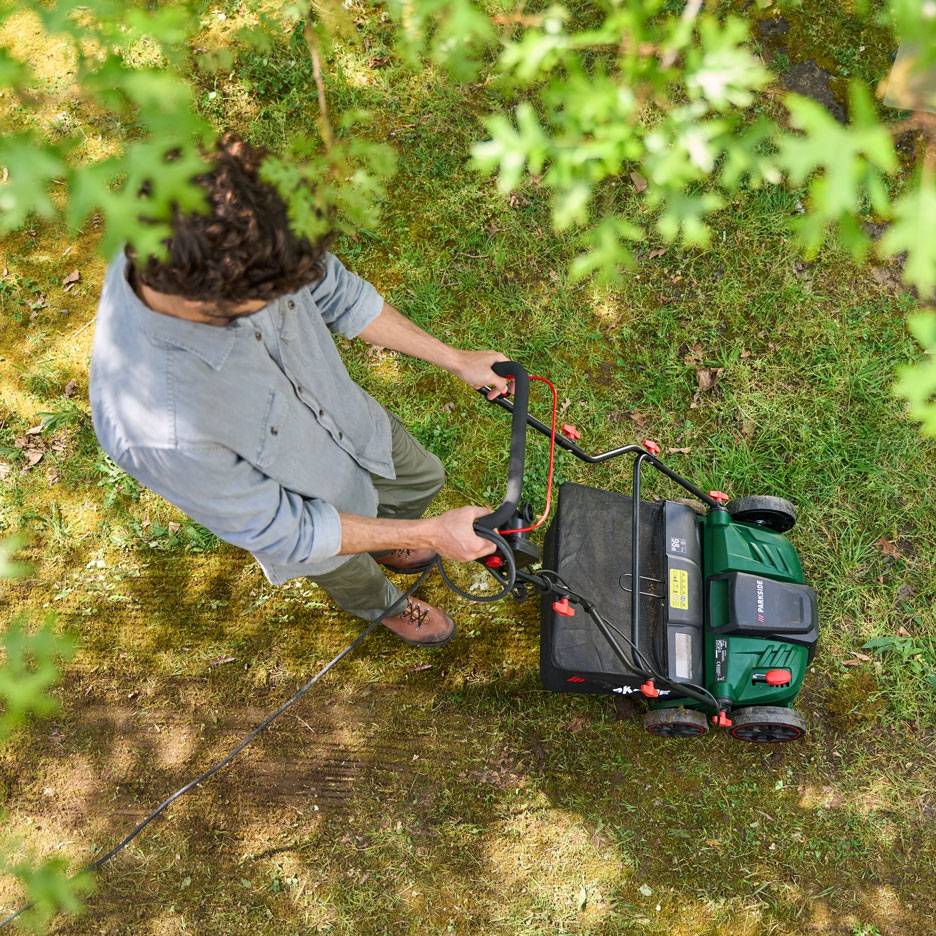 Man mowing lawn with an electric lawnmower, seen from above.