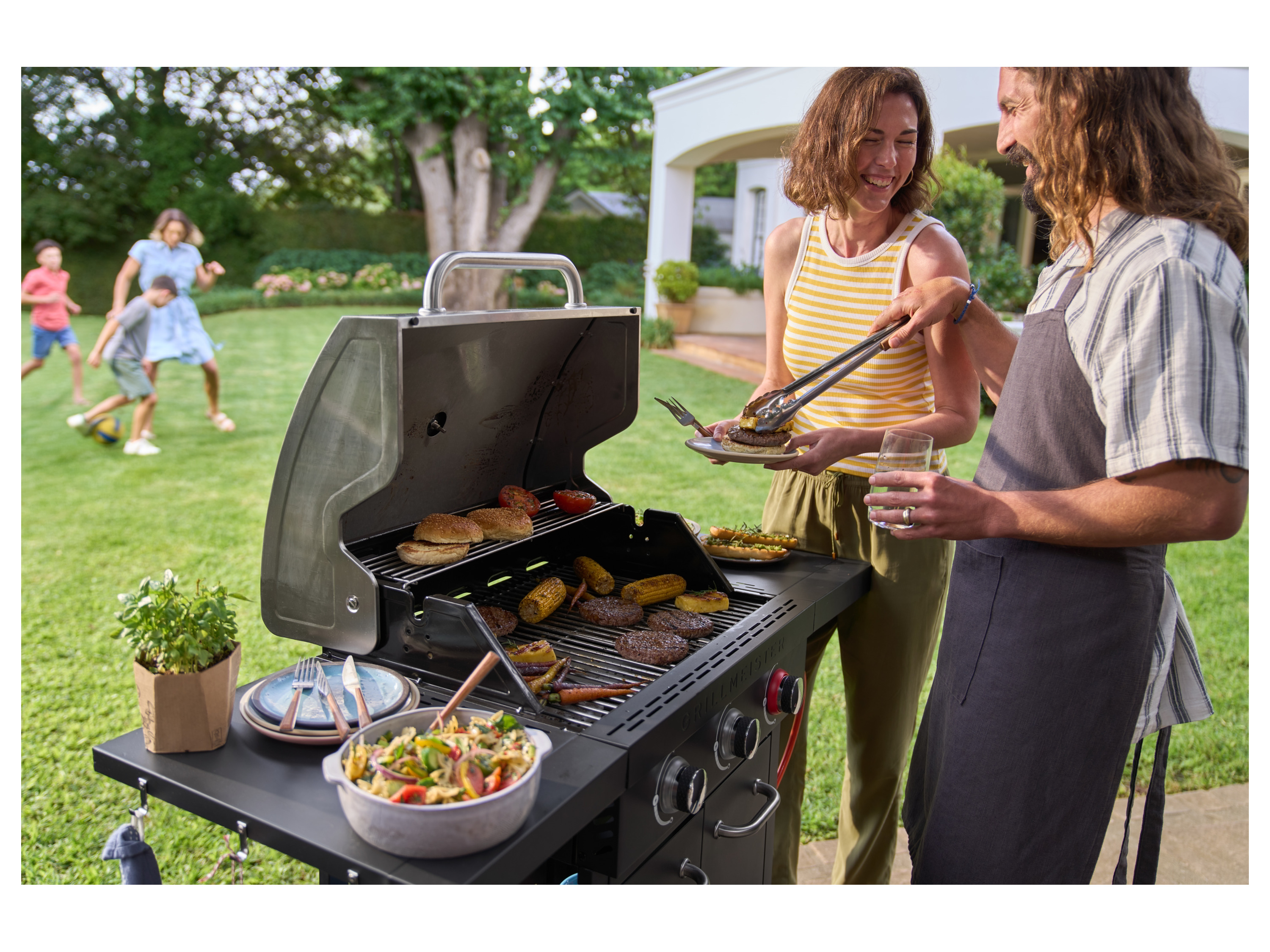A family enjoys a backyard barbecue using a Grillmeister gas grill.