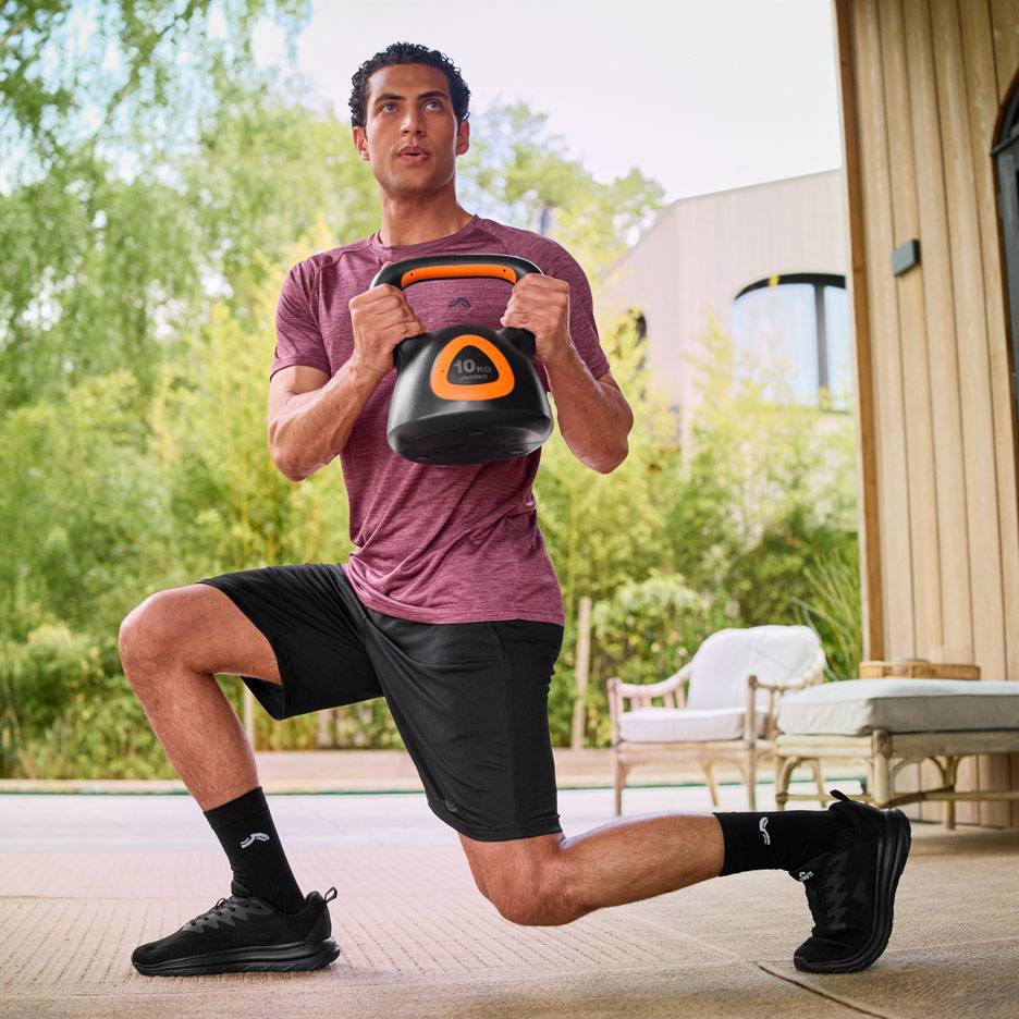 Man performing lunges with a 10 kg kettlebell outdoors.